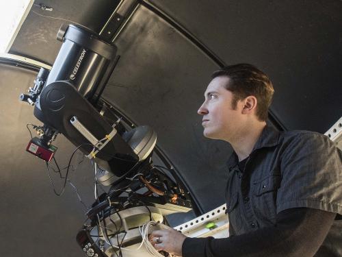 Physics student using a telescope in the observatory lab.