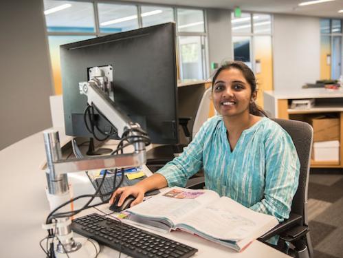 Student worker sitting at a computer in the library