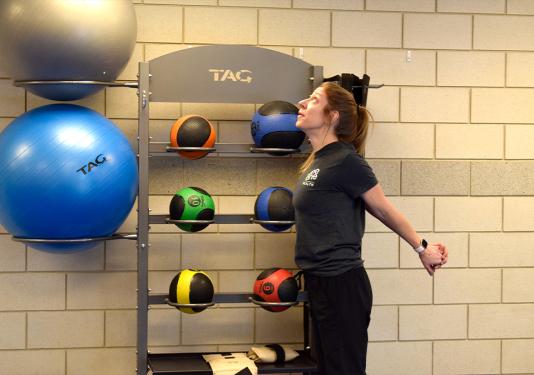 Health coach Lindsay Bloom showing a standing stretch exercise
