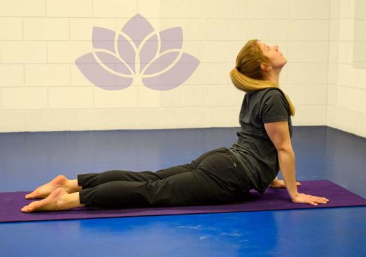 Health coach demonstrating cobra yoga pose