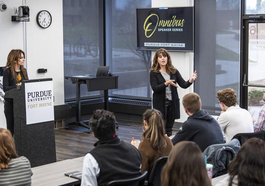 Monica Lewinsky speaks to a class while Farah Combs stands at the podium