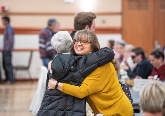 Faculty hug each other.