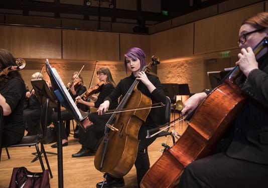 Musicians stand together playing instruments.