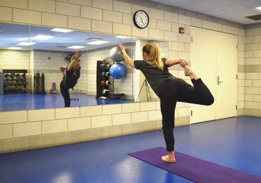 Employee Yoga class instructor demonstrating a standing balance pose