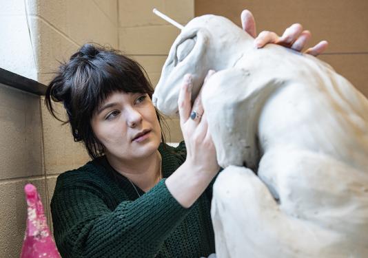 Emily Whisman is sculpting in an art studio