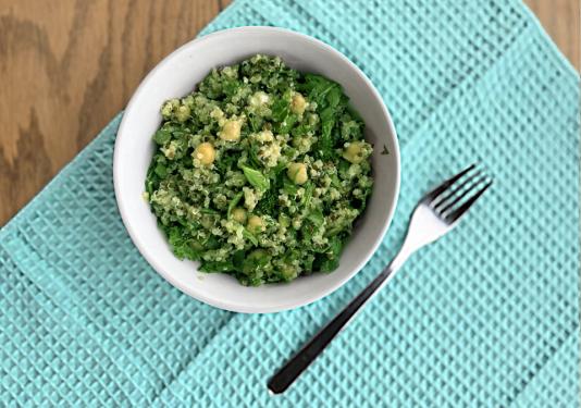 Bowl of herbed quinoa and chickpea salad with spoon on turquoise placemat served for Meatless Mondays