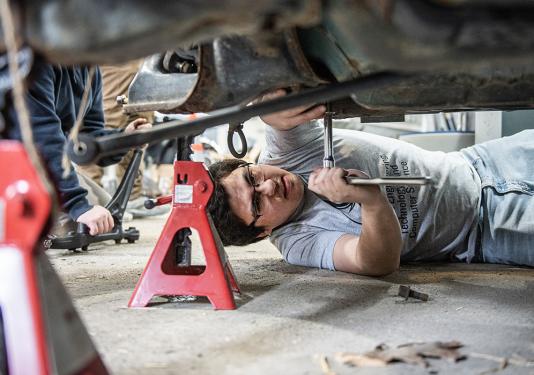 An engineering student is working under a vehicle
