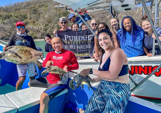 PFW marine biology students and faculty display turtles on a boat