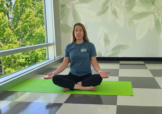 Health coach demostrating the seated meditation yoga pose in a calming environment
