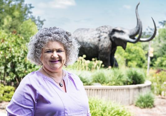 Kim De Leon is standing in front of the bronze mastodon statue.