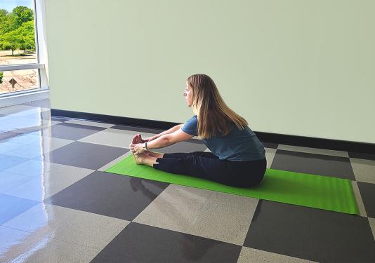 Health coach demonstrating a seated stretch for yoga class