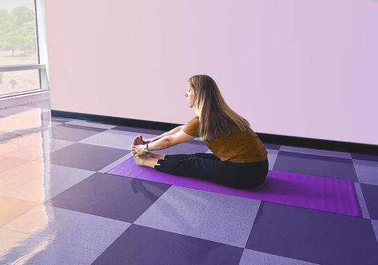Female yoga instructor sitting on a purple yoga mat showing the seated stretch pose.