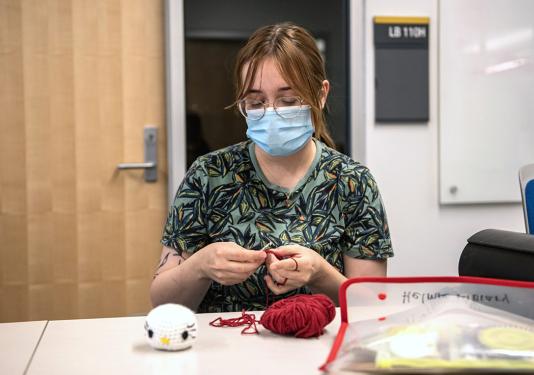 A person holds a crochet hook and yarn.