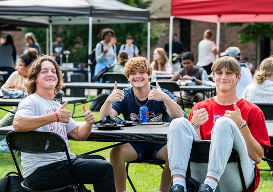 Three students are enjoying a campus kickoff event.