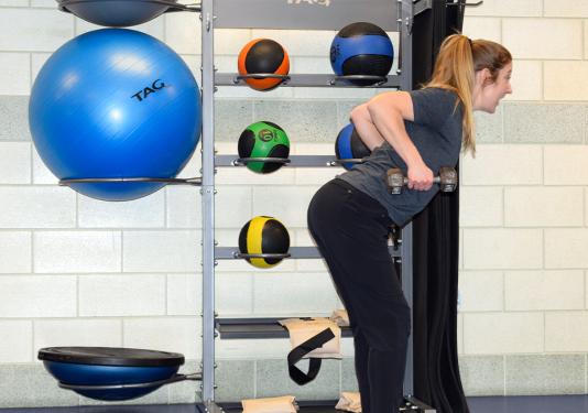 Female fitness instructor showing how to do tricep curls for strenght training class