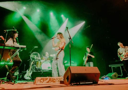 people singing on stage with green spotlights