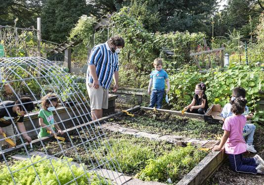 An adult and several children are working in the School of Education's urban garden.
