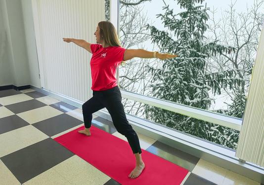 Yoga instructor showing how to do a warrior pose for February's Employee Yoga class.