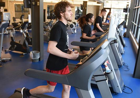 Male and female students working out on treadmills at the Fitness Center