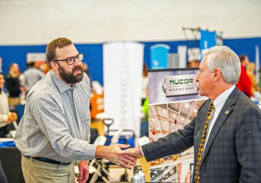 Chancellor shaking hands with a guest at the career expo.