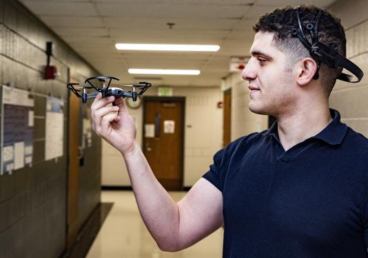 Abdelrahman Gad inspects a small, four-propeller drone.