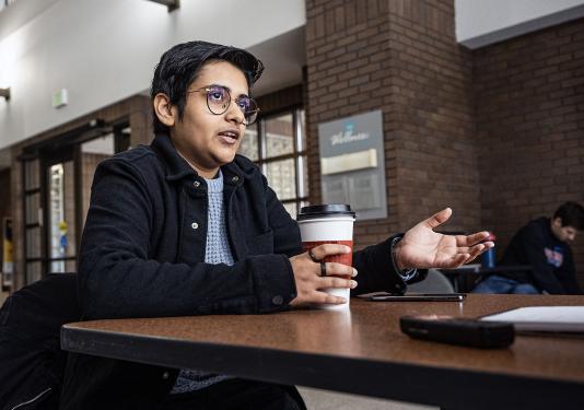 Yashi Yadav is sitting at a table and speaking to someone.