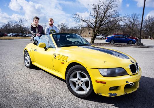 Two engineering students are siting in a restored BMW