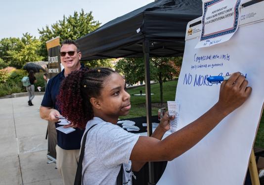 Student writes on a poster about Constitution Day.