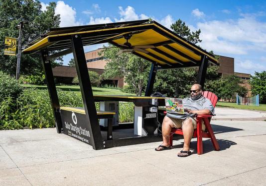Buck Jordan is working on his computer at the outdoor solar charging station