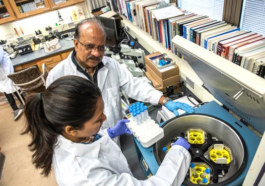 Ahmed Mustafa working with a student in a biology lab.