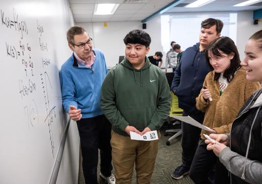 Students and a professor solving a math problem