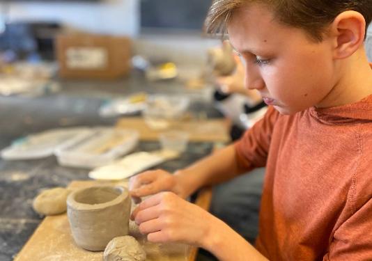 young boy making pottery