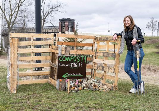 Emma Coville is standing next to compost bin