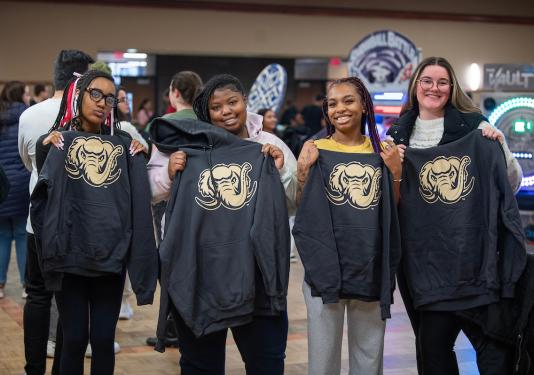 Students hold up Mastodon-printed sweatshirts.