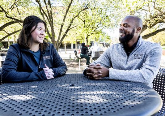 Madeline Minobe and DeShawn Woods are sitting at a table