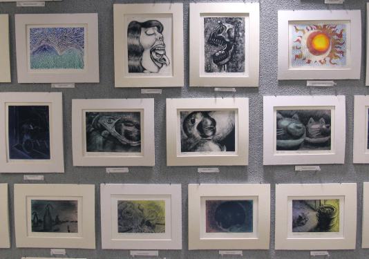 a wall of student framed student artwork