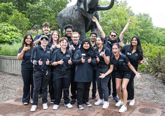 Student coaches in front of the mastodon statue