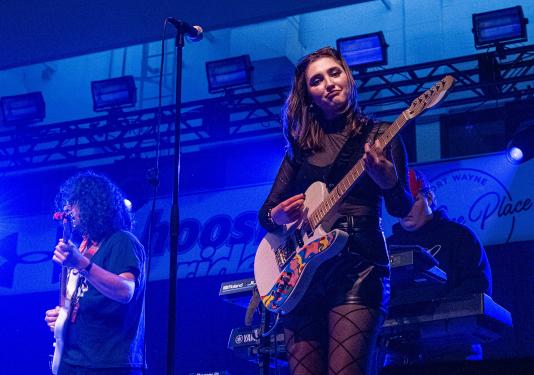 Hailee Richmond is playing guitar while performing with a band