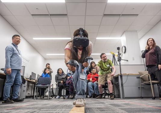 A student is walking on a balance beam while wearing a VR headset