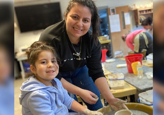 child and mother making clay pottery