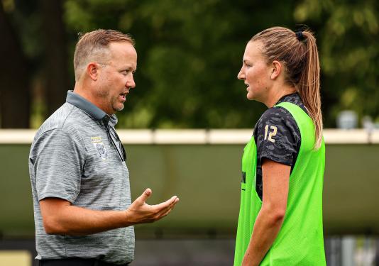 A coach is conferring with a soccer player
