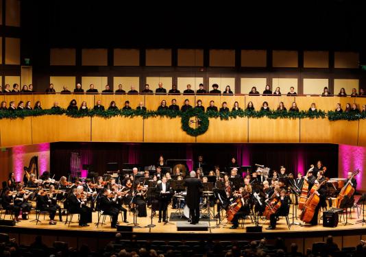Choirs and an orchestra on stage at a holiday concert