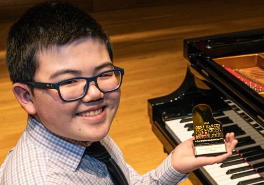 child holding trophy next to piano