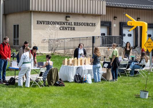 Several people are at tables outside of the Environmental Resources Center