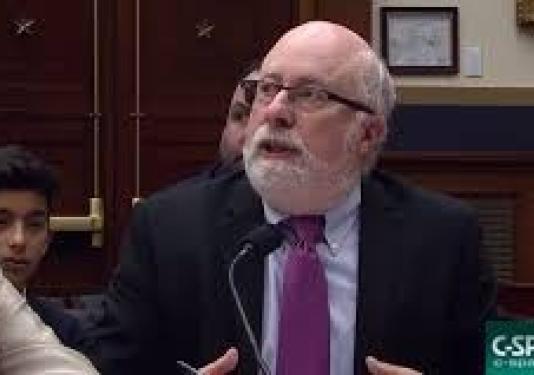 Image of Kenneth Stern, a balding white man with a trim white beard wearing glasses, a suit, and a purple tie.