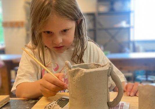 child painting pottery