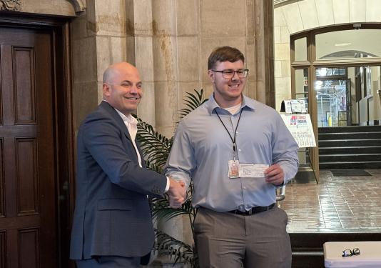 Truman Wirtz is holding a check and shaking someone's hand