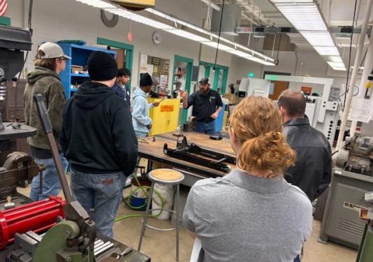 Professor teaching high school students in mechanical engineering lab