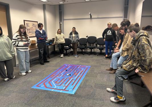 High school students gathered to race robots on mat on the floor