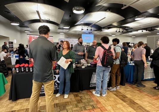 Students speaking with prospective future employers at career fair booth